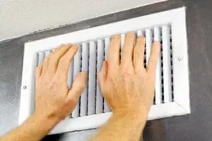person putting their hands over an air conditioning vent to feel the air coming out