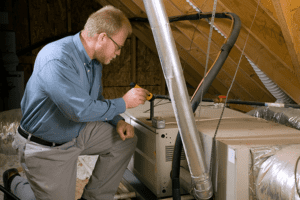 A man works on a furnace. How Do I Know I Have a Cracked Heat Exchanger?
