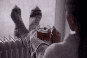 woman sitting near her furnace drinking tea.