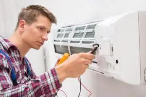 man adjusting and fixing a ductless unit.