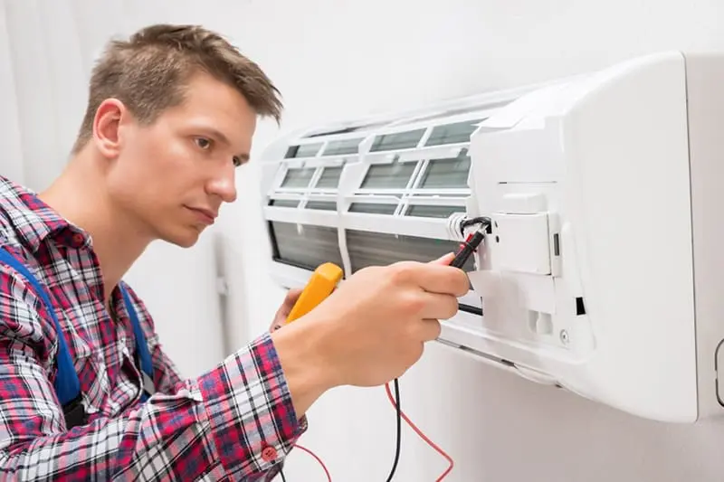FAQ - Just Right man adjusting and fixing a ductless unit.
