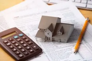 Image of calculator and model of home. How to Lower Your Energy Bills.
