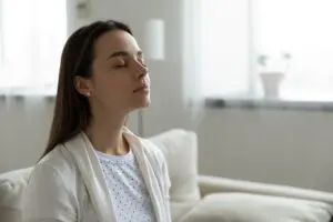 Why Do I Need a Humidifier? Woman sitting on couch with eyes closed.