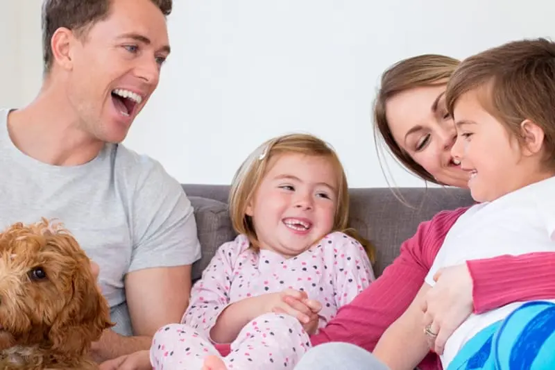 Blogs - Just Right happy family sitting close together on couch.