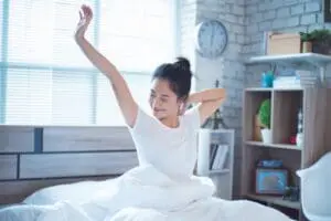 A woman wakes up feeling rested and comfortable due to her energy-efficient cooling system.