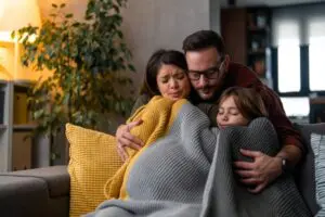 family shivering underneath a blanket