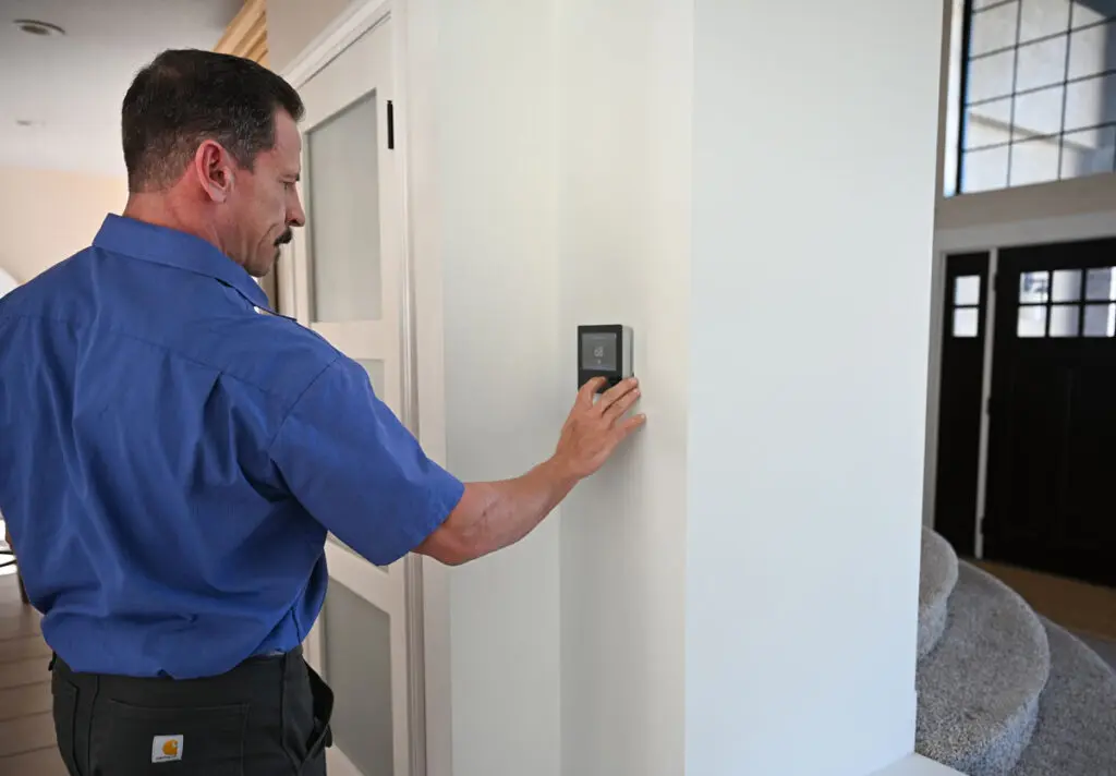 just right team member adjusting the temperature on a thermostat