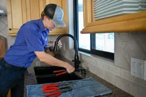 Professional plumber in Davis County, UT fixing kitchen sink leak