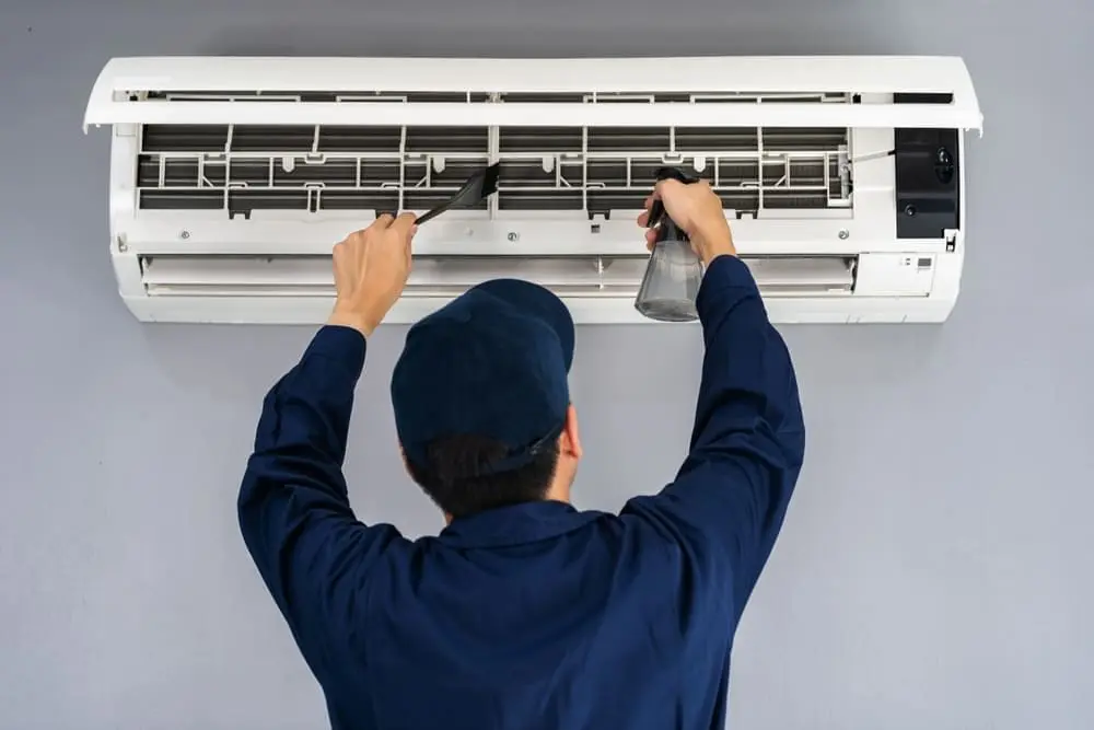 AC Maintenance American Fork UT service from Just Right Plumbing, Heating & Cooling shows an HVAC technician cleaning a wall-mounted ductless mini split air conditioning system inside a residential property. The image includes an open mini split unit, visible air filters, a cleaning brush, and spray bottle during a cooling system maintenance visit. Just Right Plumbing, Heating & Cooling provides AC maintenance, mini split cleaning, and residential HVAC inspections for homeowners in American Fork, UT.