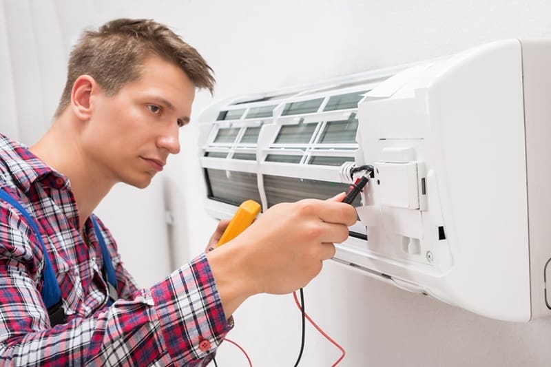 FAQ - Just Right man adjusting and fixing a ductless unit.