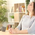 woman breathing deeply seated at desk in home office.