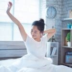 A woman wakes up feeling rested and comfortable due to her energy-efficient cooling system.