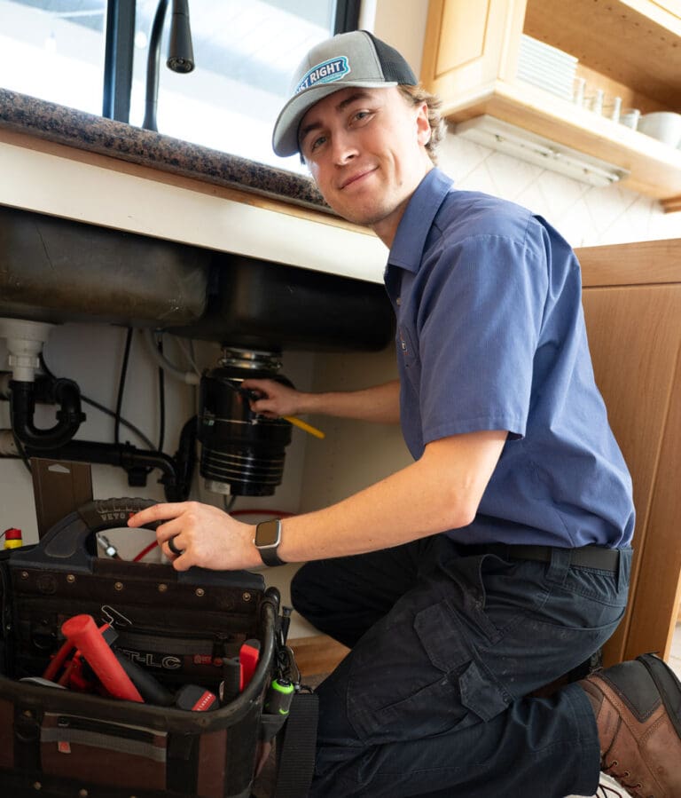 just right team member smiling while repairing pipes under a kitchen sink