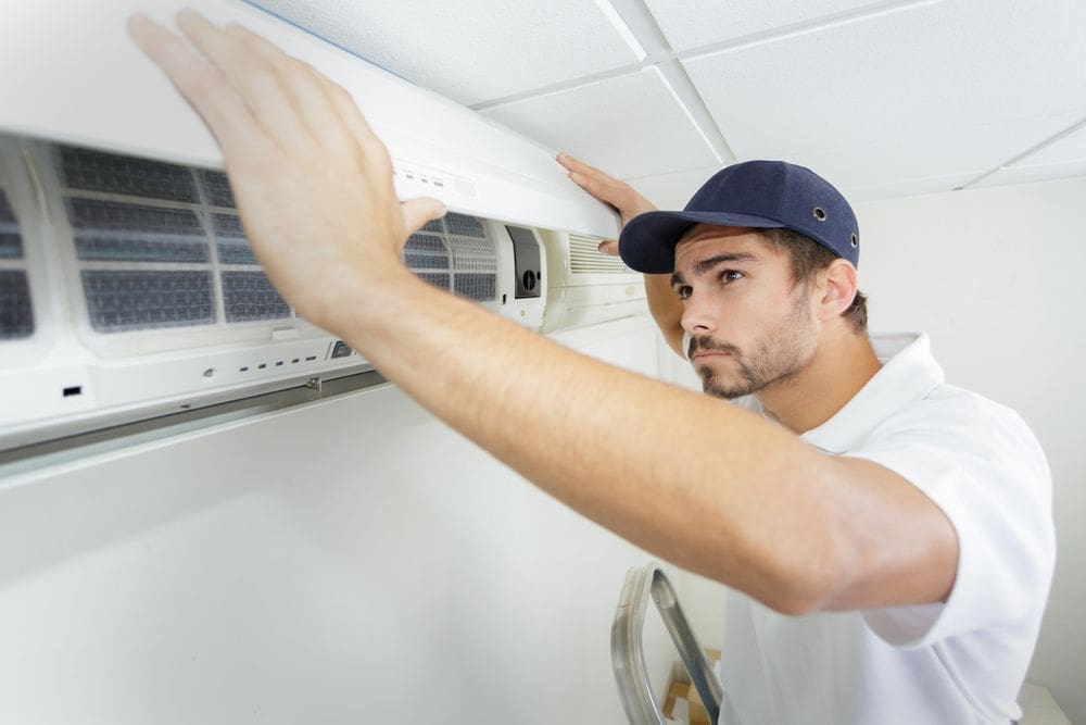 technician finishes installing residential ac unit