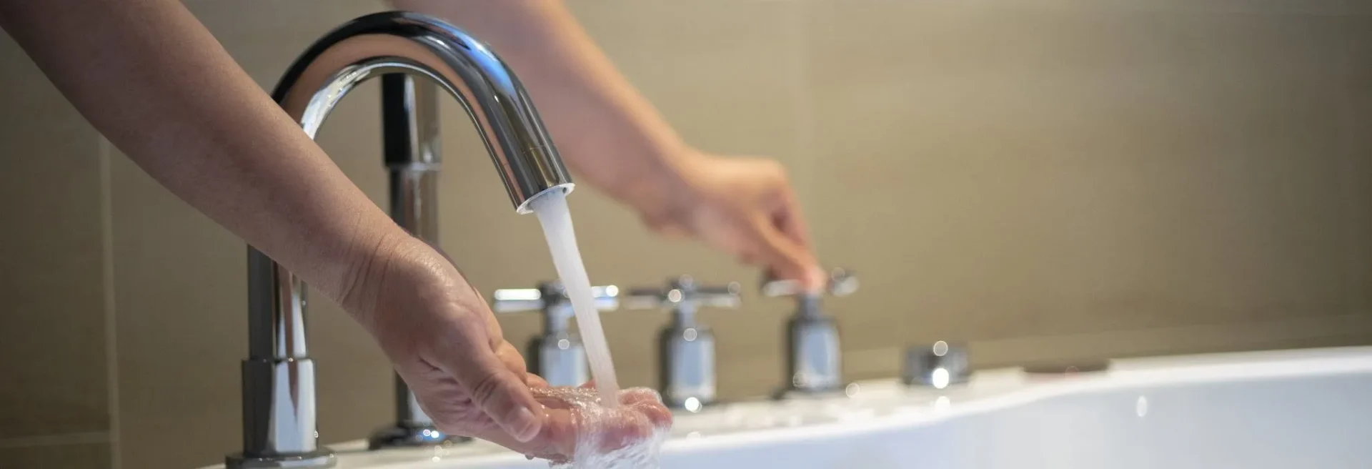 person turning on a faucet and checking the water
