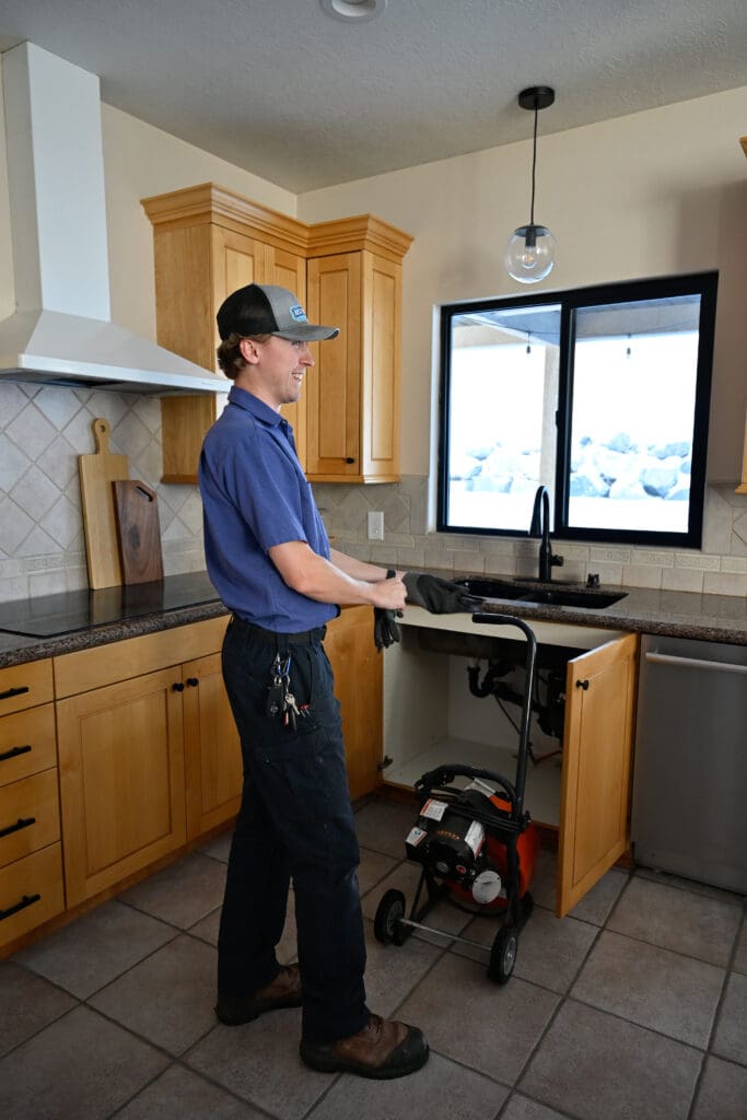 Professional plumber in Sandy, UT repairing kitchen plumbing system