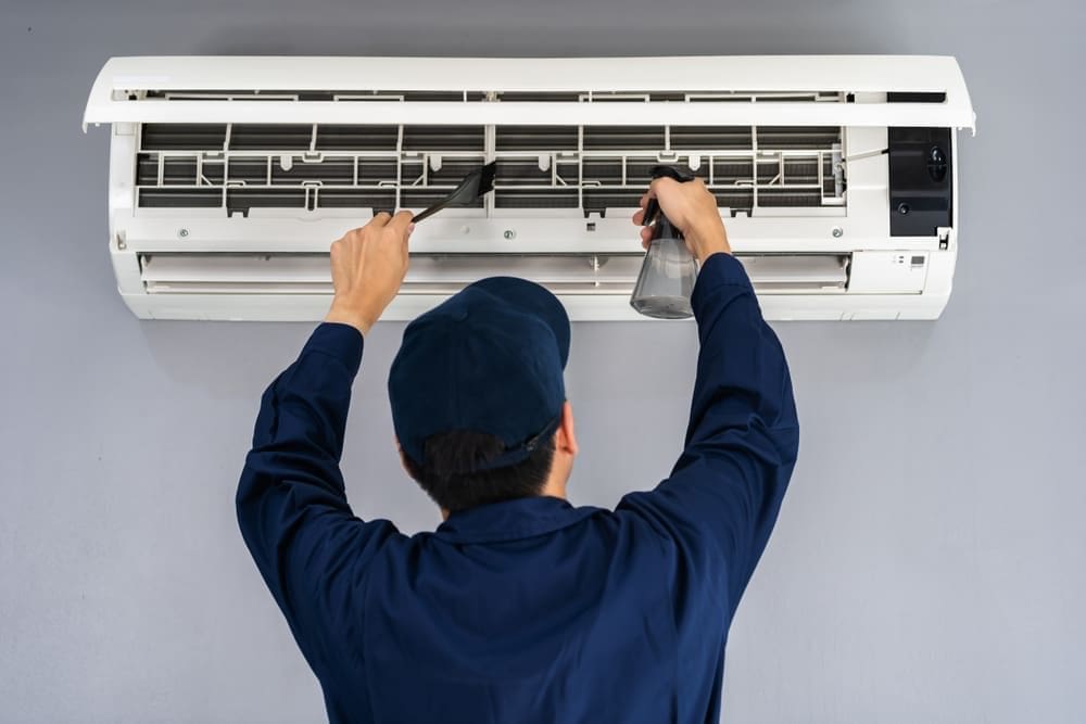 AC Maintenance American Fork UT service from Just Right Plumbing, Heating & Cooling shows an HVAC technician cleaning a wall-mounted ductless mini split air conditioning system inside a residential property. The image includes an open mini split unit, visible air filters, a cleaning brush, and spray bottle during a cooling system maintenance visit. Just Right Plumbing, Heating & Cooling provides AC maintenance, mini split cleaning, and residential HVAC inspections for homeowners in American Fork, UT.