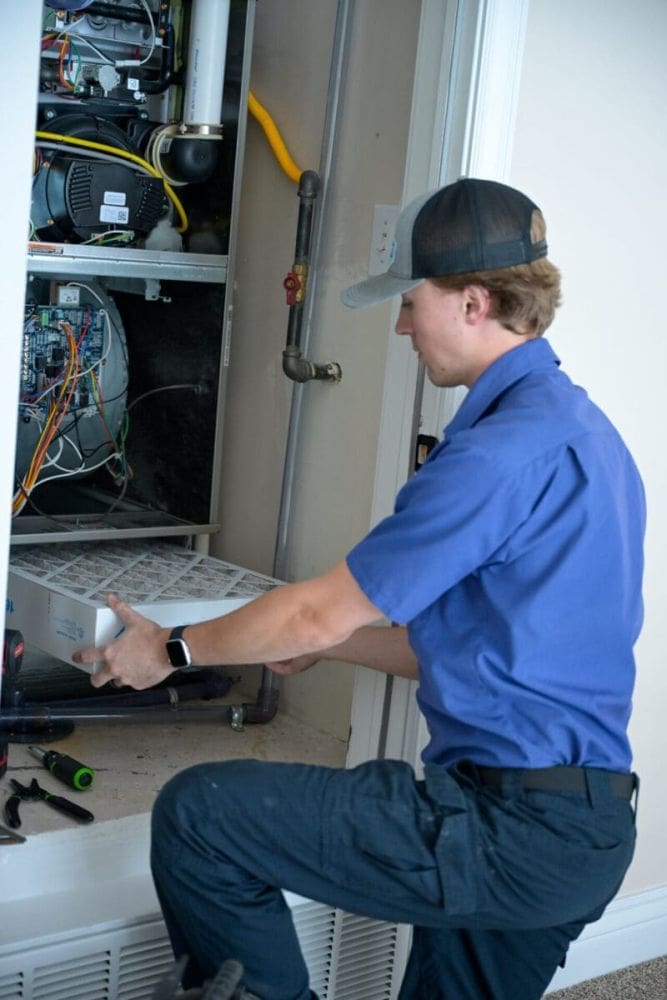 HVAC technician replacing an air filter during AC maintenance in Layton UT inside a residential HVAC system closet. The image shows a technician performing indoor cooling system maintenance while handling a clean HVAC filter beside exposed furnace and air handler components. Just Right Plumbing, Heating & Cooling provides AC maintenance, HVAC inspections, and air filter replacement services for homeowners in Layton, Utah. Customers needing AC maintenance in Layton UT can call Just Right Plumbing, Heating & Cooling at (801) 771-1510 for cooling tune-ups, indoor HVAC maintenance, and seasonal air conditioning service.
