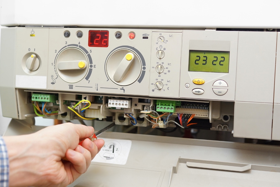 A gas furnace is being fixed. What to Do When Your Furnace Is Leaking Water.