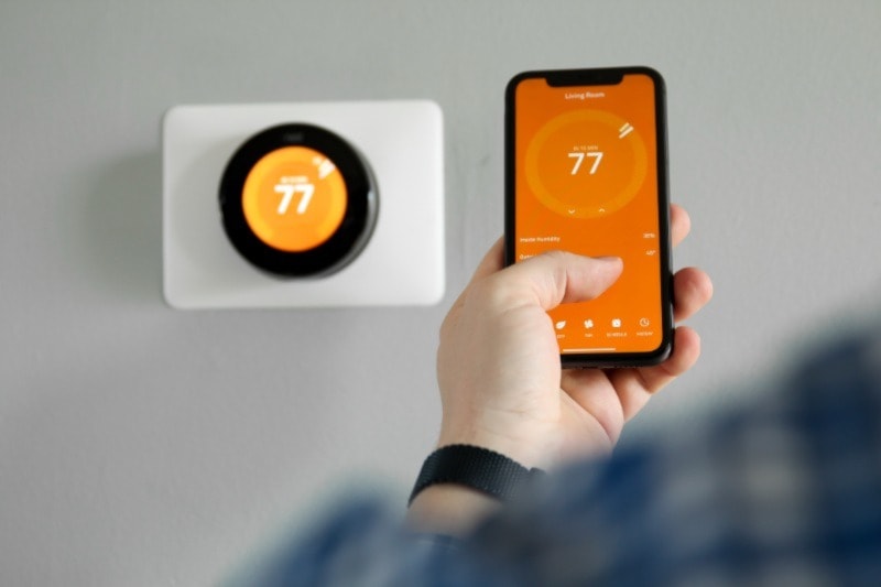 Homeowner using their smartphone on the smart thermostat